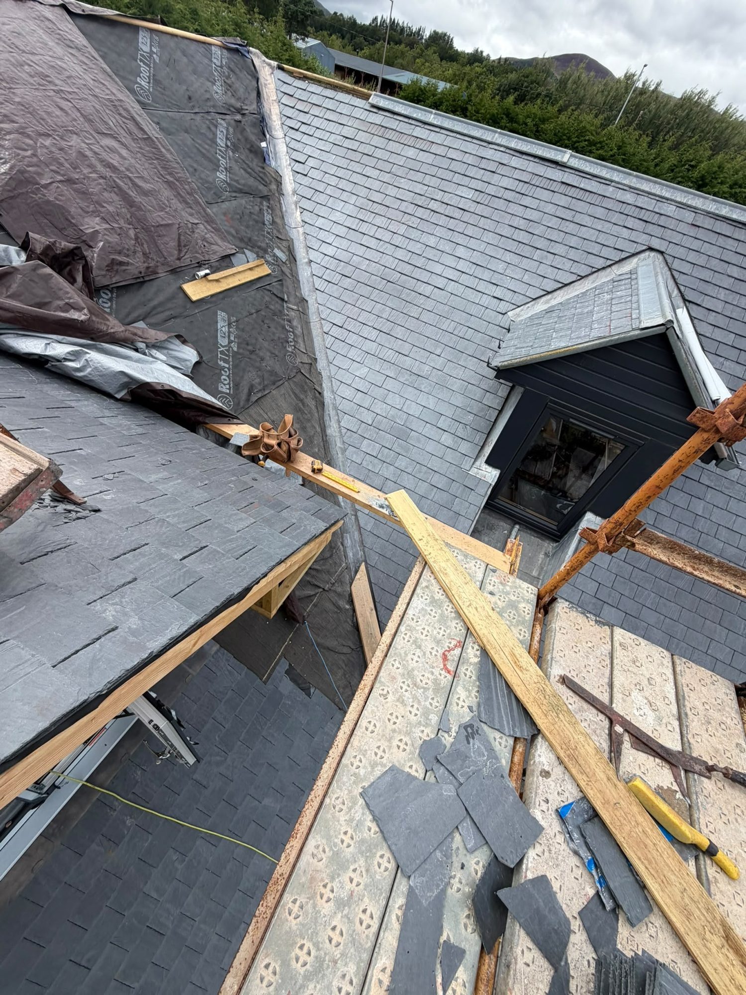 Emergency roof repair in progress on a slate roof with scaffold and new battens, Edinburgh